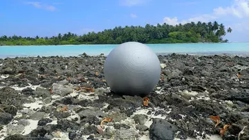 A large plastic sports ball on a beach 