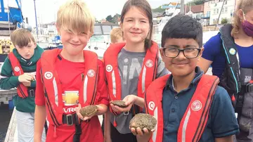 Kids holding oysters as part of Wild Oyster Project education. 
