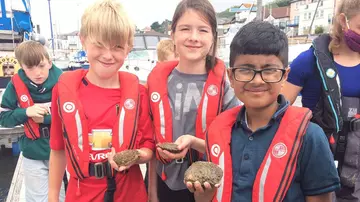 Kids holding oysters as part of Wild Oyster Project education.