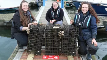 Three conservationists posing with crates of oysters