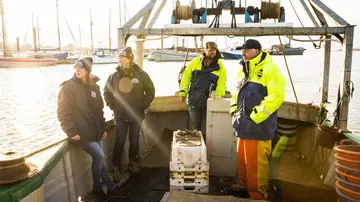 ENORI project fieldwork - Two ZSL conservationists on boat with two men in hi vis jackets. 