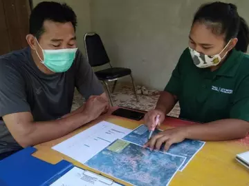 Gib Thampitak working with community member planning surveys on maps with team