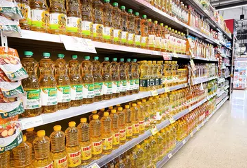 supermarket shelves stacked with bottles of yellow coloured cooking oil