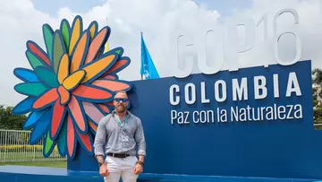 James Pilktington stood in front of COP16 signage