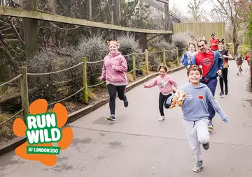 A family wearing animal ears running through London Zoo with a Run Wild logo in the bottom left corner of the image