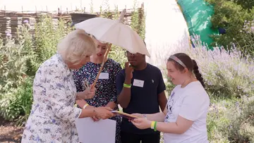 HRM Queen Camilla presented a new Winnie the Pooh book by EAS student next to Winnie the bear statue at London Zoo