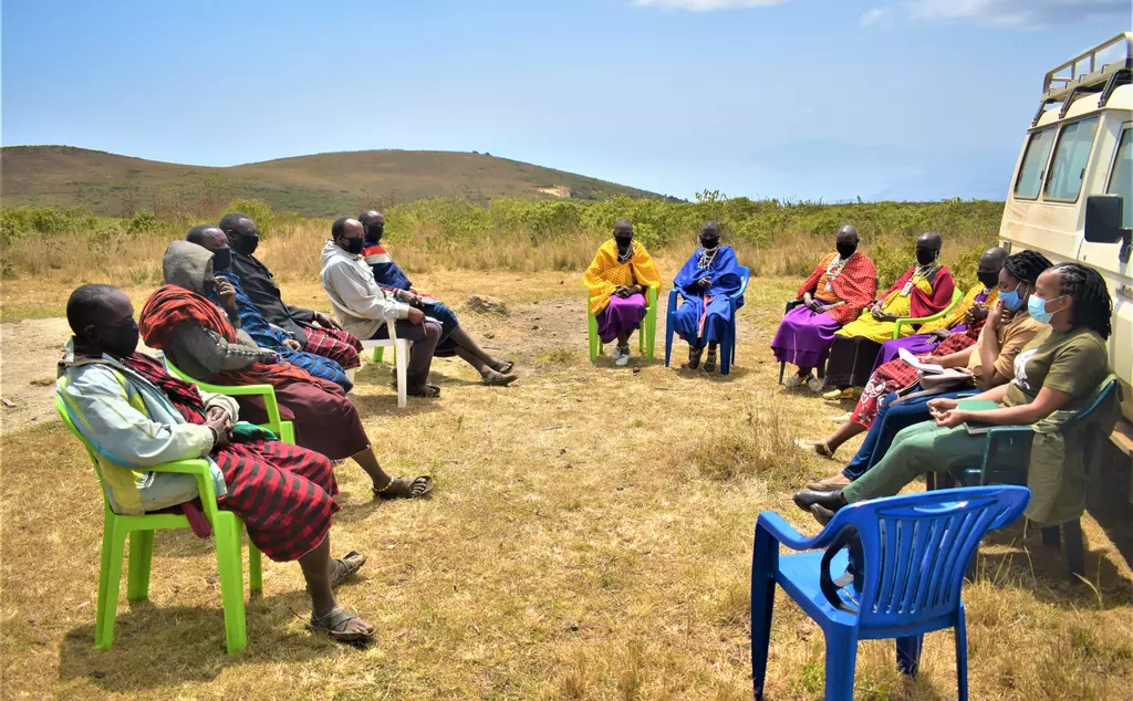 Alaililai group sitting on chairs in a circle holding a discussion on grievance feedback mechanism in Longido ward