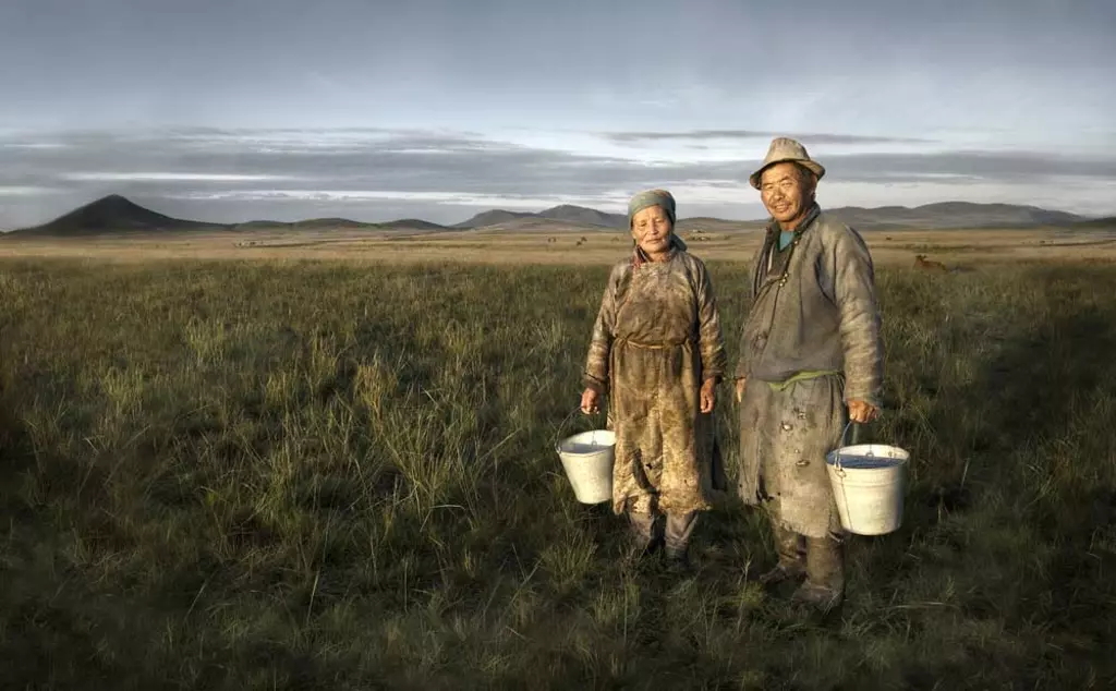 Farmers in Mongolia holding basin and posing in the expansive Steppes landscape