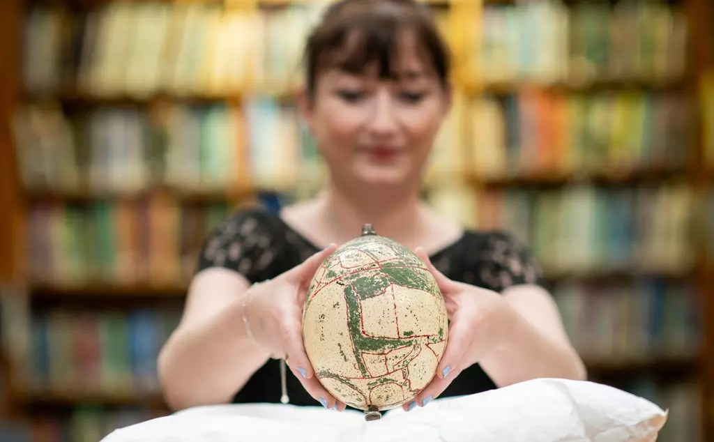 Woman holding an ostrich egg with a map of Whipsnade zoo painted on it