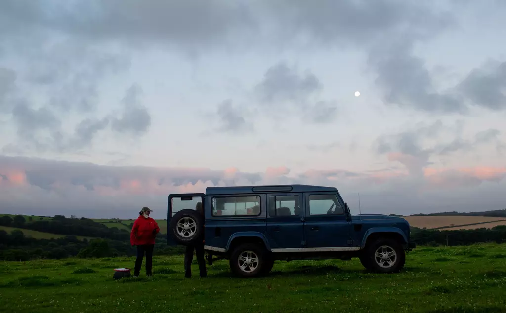 Team standing by car at dusk 