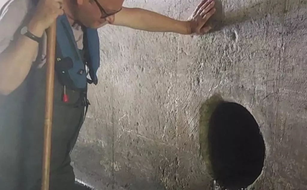 Matthew Gould standing next to a sewer outlet