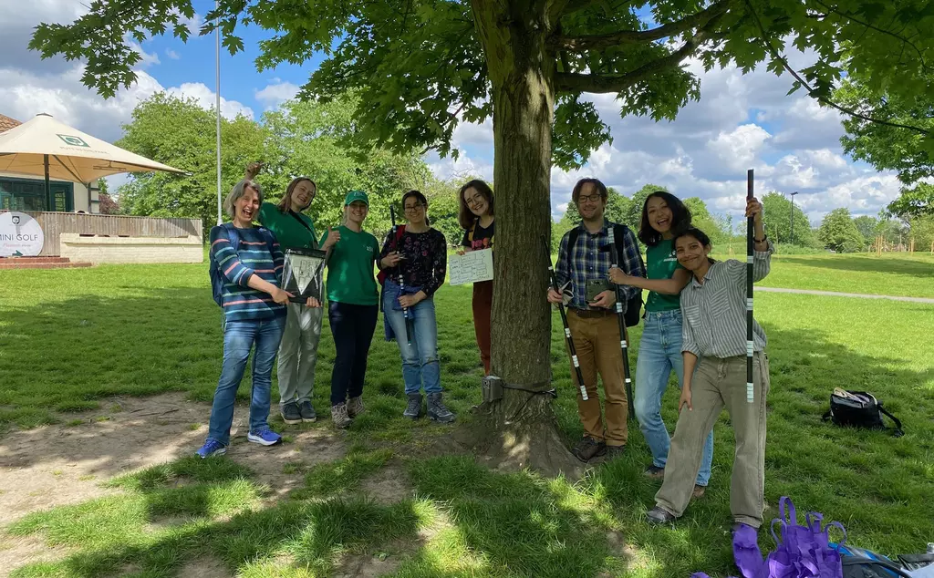 Group of volunteers smiling in front of a camera trap attached to a tree