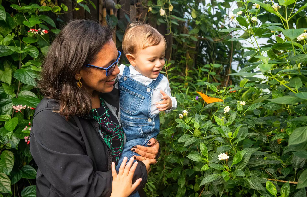 Woman shows child a butterfly in the butterfly habitat at London Zoo 