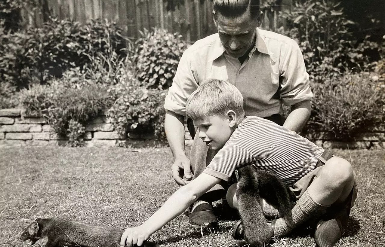 A black and white photo of a father and son in the garden with pine marten kits