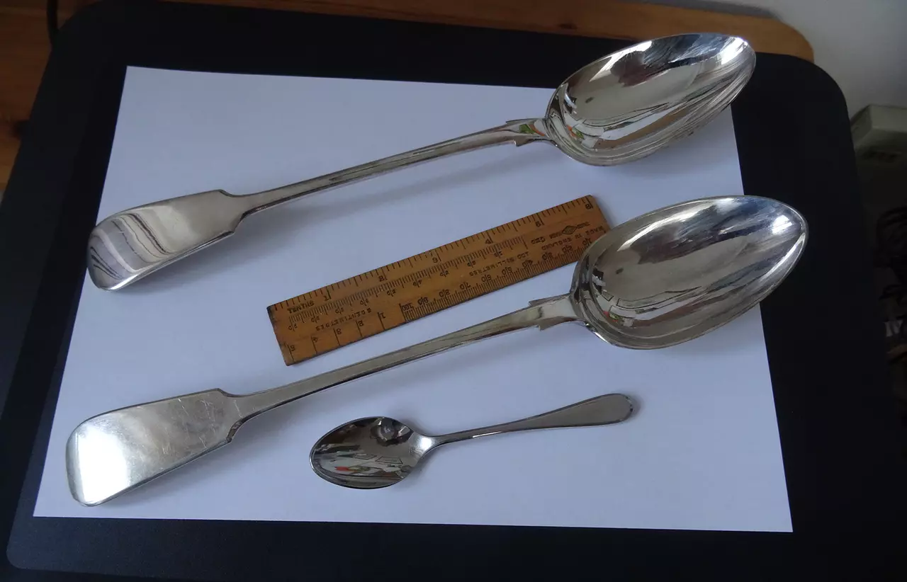 Three spoons set out against a ruler on a piece of white paper