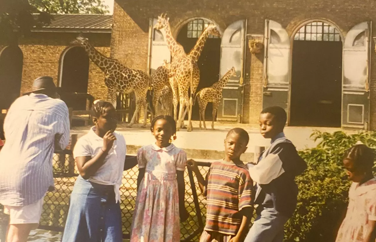 A group of children standing outside London Zoo's Giraffe House with giraffes in the background