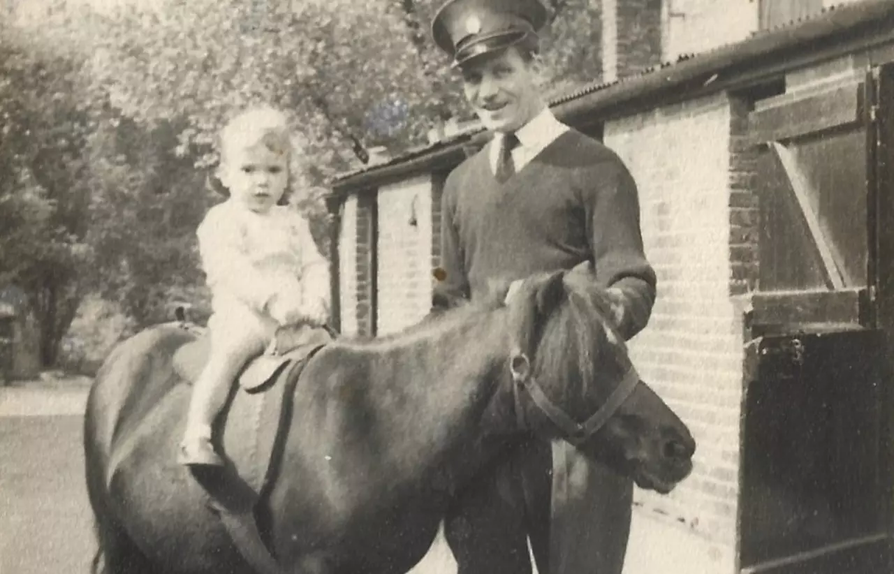 A black and white photograph of a child on a pony with a zookeeper standing next to them