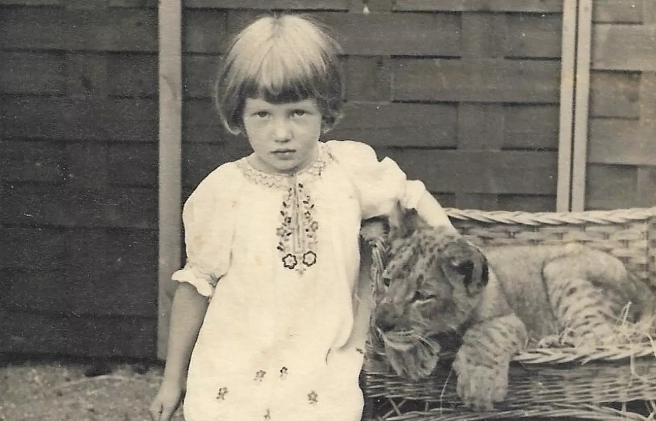 A black and white photograph of a child with a lion cub