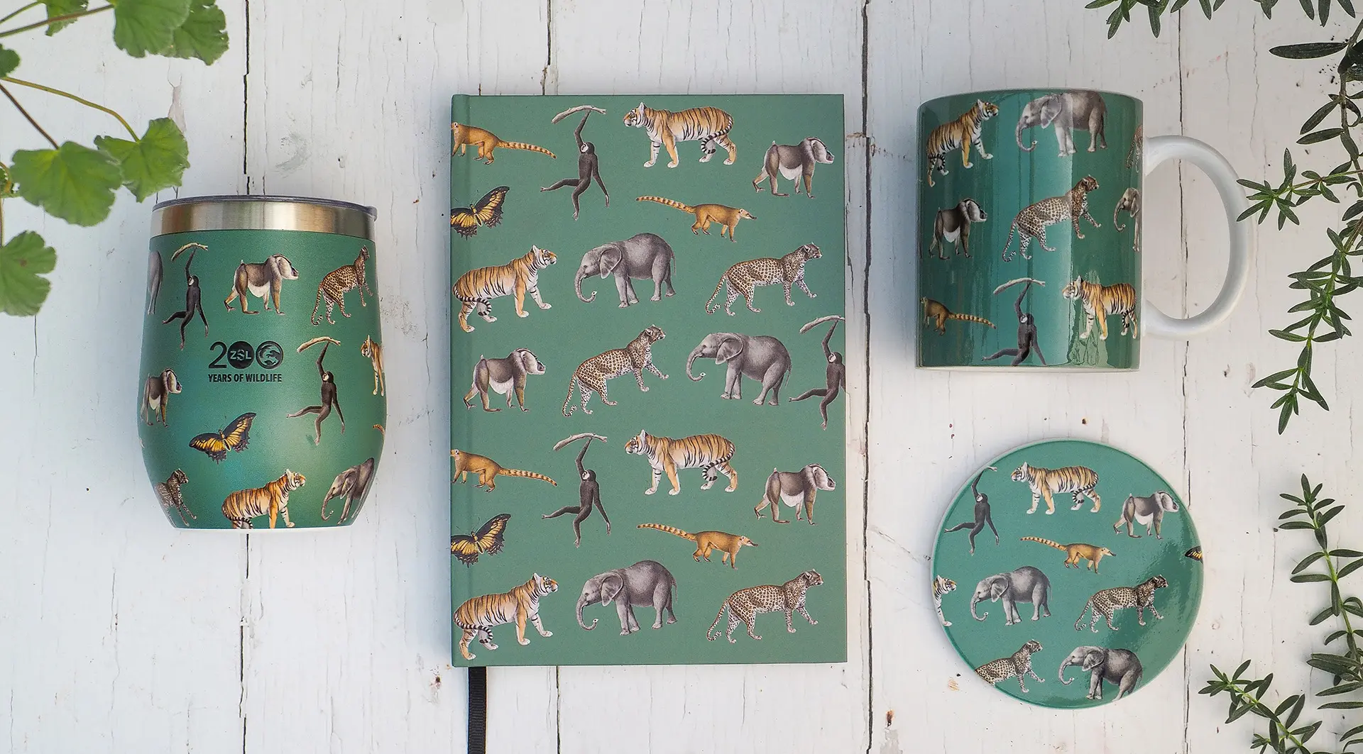 A notepad, travel mug, ceramic mug and coaster in a green design with animals on