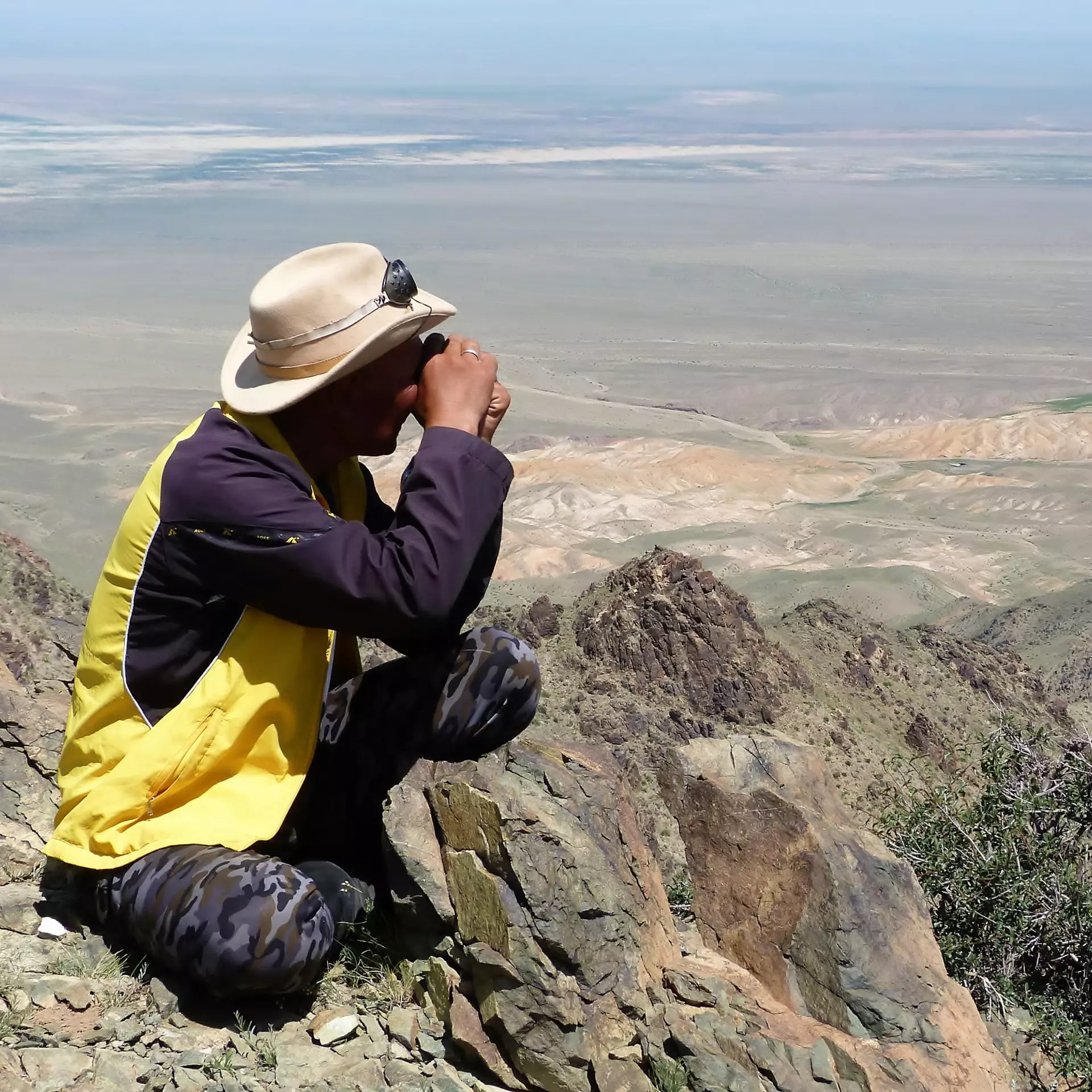 ZSL conservationist looking out with binoculars across Mongolian steppe plains