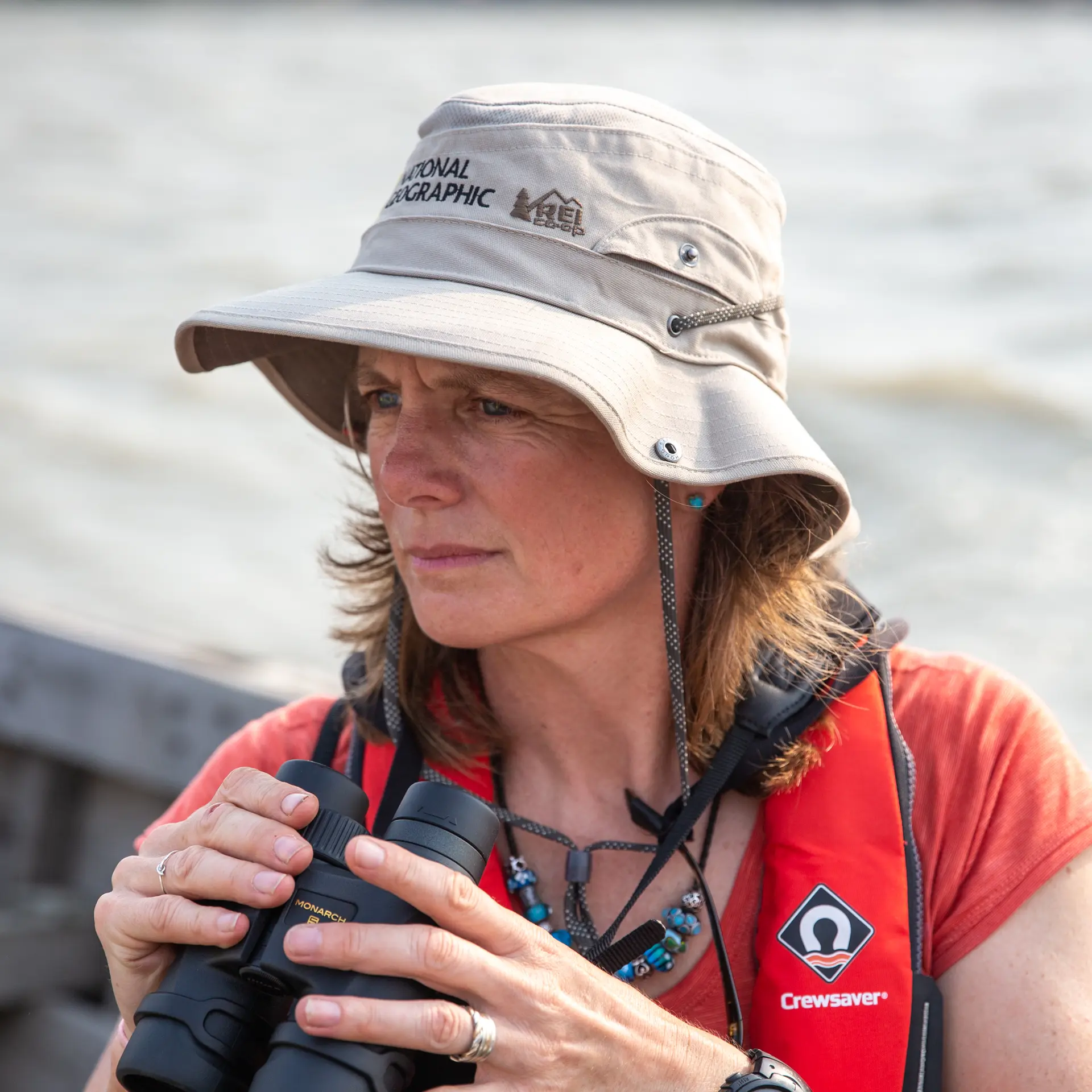 Heather Koldewey on a riverboat looking in the distance with binoculars in hand