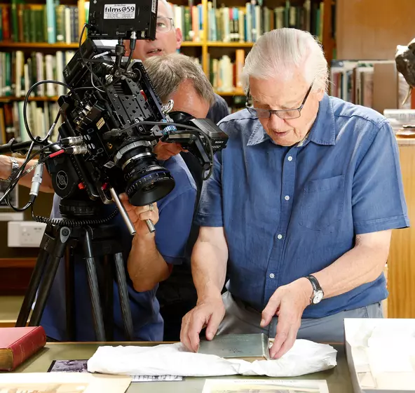 David Attenborough looking at archives in the ZSL library with a film crew