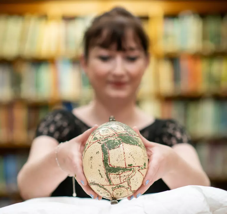 Woman holding an ostrich egg with a map of Whipsnade zoo painted on it