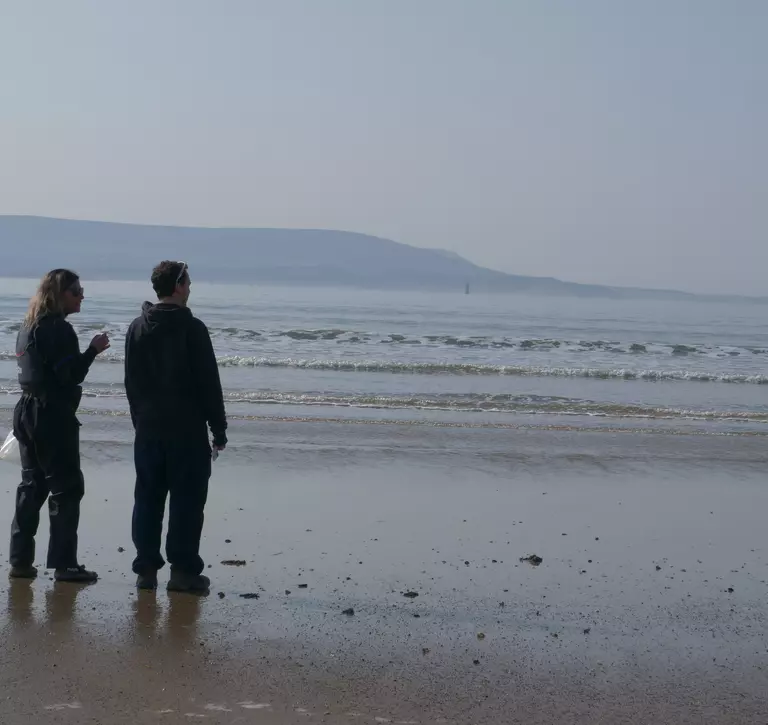 Two scientists stood on a Welsh beach