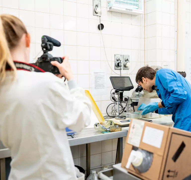 Pathologist uses microscope and another person films them