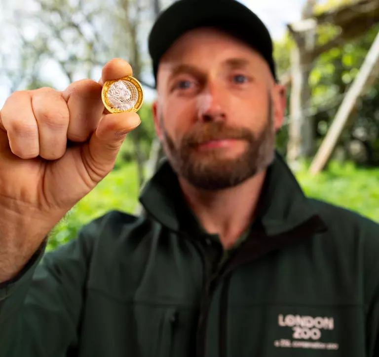 Keeper holding a commemorative £2 coin